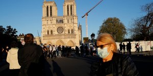 Πολίτης με μάσκα στο Παρίσι, με φόντο την Παναγία των Παρισίων, εν μέσω κορωνοϊού