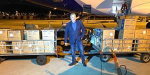 O Γιώργος Πατούλης ποζάρει μπροστά από αεροπλάνο και κούτες με μάσκες