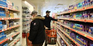 Καταναλωτές ψωνίζουν από ράφια σούπερ μάρκετ