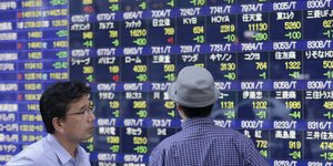 Επενδυτές μπροστά σε πίνακα μετοχών χρηματιστηρίου