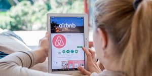 Γυναίκα επισκέπτεται την ιστοσελίδα του Airbnb μέσα από το τάμπλετ της