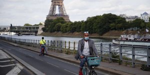 Ανδρας κάνει ποδήλατο φορώντας μάσκα για τον κορωνοϊό στις όχθες του Σηκουάνα