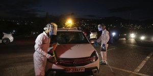 Άνδρες στο Ιράν με μάσκα και στολή απολυμαίνουν αυτοκίνητο