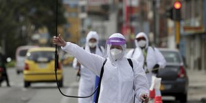 Άνθρωποι με στολές και μάσκες απολυμαίνουν δημόσιους χώρους