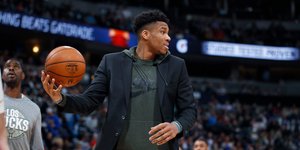 Ο Γιάννης Αντετοκούνμπο με μπάλα στα χέρια φορώντας τζάκετ