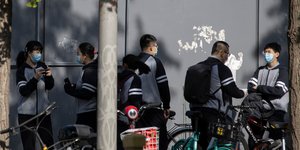 Ανδρες και γυναίκες κάνουν ποδήλατο στην Κίνα εν μέσω της πανδημίας