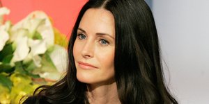 Η Κόρτνεϊ Κοξ με μαύρη μπλούζα και χρυσή αλυσίδα στον λαιμό 