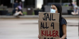 Διαδηλωτής με αφορμή τη δολοφονία του Τζορτζ Φλόιντ με πλακάτ που γράφει «Φυλακή για τους 4 δολοφόνους αστυνομικούς»