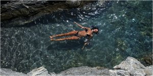 Γυναίκα ξαπλωμένη στην επιφάνεια της θάλασσας στην Αμοργό