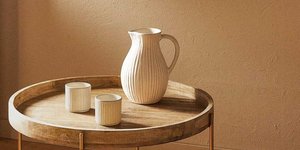 Κανάτα μπεζ με δύο ποτήρια μπεζ σε ξύλινο τραπέζι