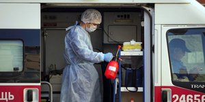 Άνδρας με στολή, σκούφο και μάσκα προστασίας από τον κορωνοϊό, σε κινητή μονάδα υγείας στη Ρωσία