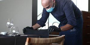 Εστίαση: Ενας εργαζόμενος με μάσκα στρώνει τραπέζι σε εστιατόριο