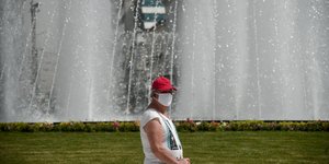 Γυναίκα με καπέλο και μάσκα για τον κορωνοϊό στο νέο συντριβάνι της Ομόνοιας