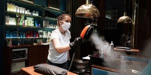 Γυναίκα ψεκάζει σε κατάστημα φορώντας υφασμάτινη μάσκα για τον κορωνοϊό