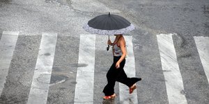 Γυναίκα περνά διάβαση κρατώντας ομπρέλα