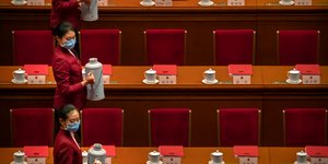 Γυναίκες με μάσκα για κορωνοϊό μεταφέρουν δοχεία στο Κινεζικό κοινοβούλιο
