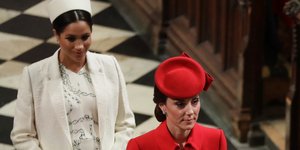 Η Κέιτ Μίντλετον με κόκκινο παλτό και η Μέγκαν Μαρκλ με λευκό παλτό