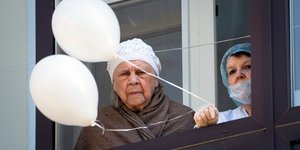 Ηλικιωμένη στο μπαλκόνι νοσοκομείου λόγω κορωνοϊού με λευκά μπαλόνια