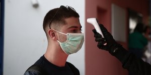 Ενας νεαρός υποβάλλεται σε θερμομέτρηση για κορωνοϊό