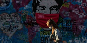 Κορωνοϊός γυναίκα με μάσκα περπατά μπροστά από γκράφιτι στην Πράγα