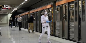 επιβάτες με μάσκες σε σταθμό του μετρό