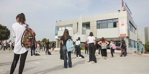 Μαθητές έξω από προαύλιο σχολείου με τις τσάντες τους