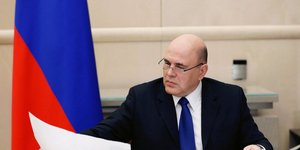 Ο Ρώσος πρωθυπουργός Μικαίλ Μισούστιν στο γραφείο του μελετά έγγραφα με φόντο τη ρωσική σημαία