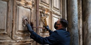 Ιερέας με μάσκα μπροστά στον Πανάγιο Τάφο