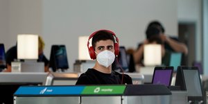Νεαρός με μάσκα για κορωνοϊό και ακουστικά σε αεροδρόμιο στις ΗΠΑ