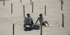 Ζευγάρι σε παραλία στη Γαλλία, οριοθετημένη με πασσάλους για την τήρηση αποστάσεων λόγω κορωνοϊού