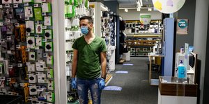 Πελάτης σε κατάστημα με μάσκα και γάντια στέκεται στα ειδικά σημάδια για την τήρηση αποστάσεων