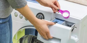 Γυναίκα βάζει σκόνη απορρυπαντικό στο πλυντήριο