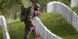 Στρατιώτης με μάσκα για τον κορωνοϊό, αφήνει αμερικανικές σημαίες σε τάφους