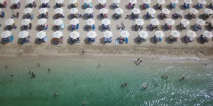 Πανοραμική εικόνα από παραλία της Ελλάδας γεμάτη με ομπρέλες