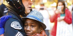 Αγοράκι φοράει καπέλο και κλαίει στην αγκαλιά ενός αστυνομικού 