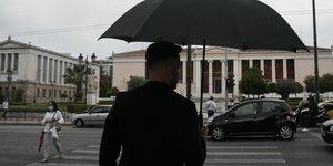 Ανδρας με μαύρα ρούχα και ομπρέλα στην Αθήνα