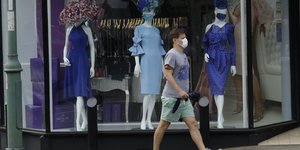 Βρετανός με μάσκα λόγω κορωνοϊού περπατά μπροστά από βιτρίνα