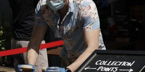 Εργαζόμενος με γάντια και μάσκα σερβίρει μπύρα σε αγγλική παμπ