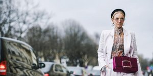 γυναίκα με λιλά παντελόνι και σακάκι περπατά στο δρόμο