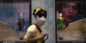 Γυναίκα με μάσκα στο δρόμο μπροστά από βιτρίνα καταστήματος