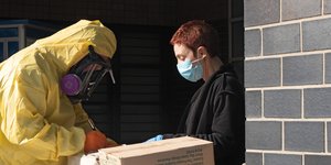 Γυναίκα φορώντας μάσκα παραλαμβάνει κούτες