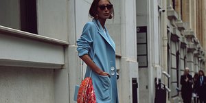 Γυναίκα με γαλάζιο σακάκι, χρυσά σκουλαρίκια, γαλάζια τσάντα, πορτοκαλί μαντήλι