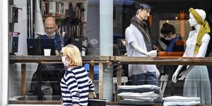 γυναίκα με μάσκα μπροστά από βιτρίνα