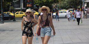 Γυναίκες με καπέλα, νερό και γυαλιά ηλίου περπατούν