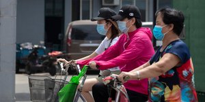 Γυναίκες κάνουν ποδήλατο φορώντας μάσκα για κορωνοϊό στην Κίνα