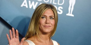 Η Τζένιφερ Άνιστον με λευκό φόρεμα χαιρετά και χαμογελά