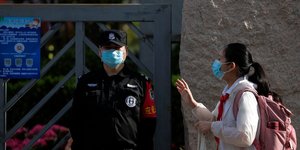 Κινέζα με μάσκα για κορωνοϊό δίπλα σε σεκιούριτι