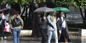 Παρέα γυναικών περπατά στη βροχή με ομπρέλες