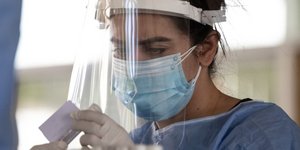 Γιατρός με μάσκα και ασπίδα προσώπου παίρνει δείγμα για έλεγχο