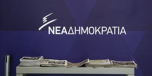 Το λογότυπο της ΝΔ σε μπλε φόντο και σώμα εφημερίδων
